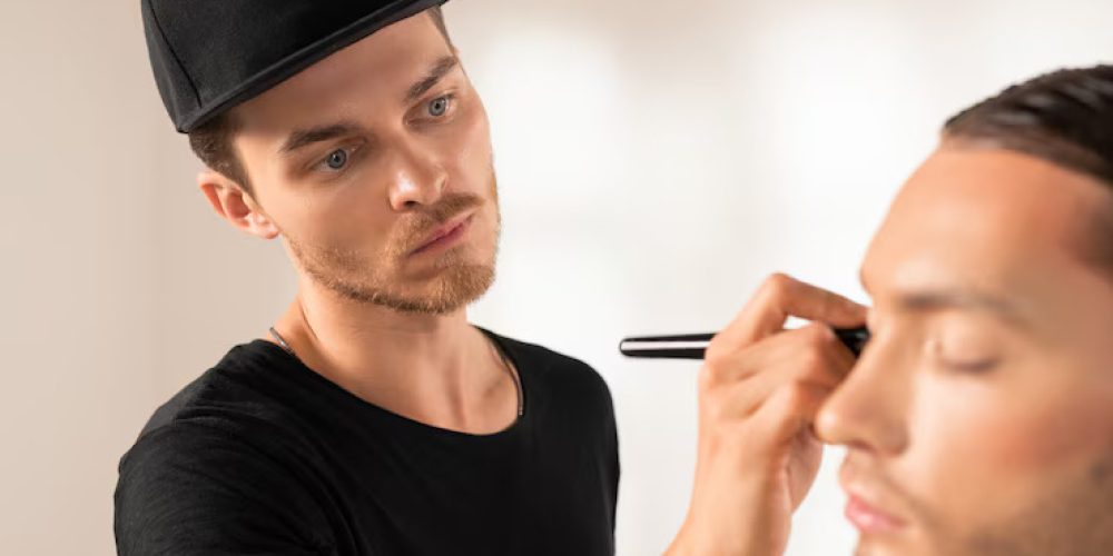 concentrated-young-man-black-cap-doing-theatrical-makeup-man-photoshoot_274679-24658