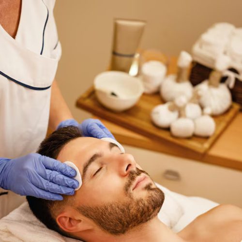 young-man-getting-face-massage-while-lying-down-with-eyes-closed-spa-center_637285-1709