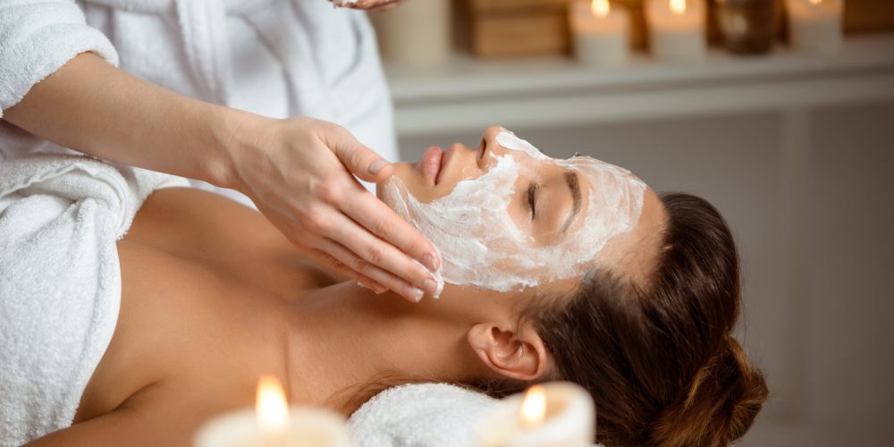 Young beautiful brunette girl in mask for face relaxing in spa salon. Eyes closed. Copy space.